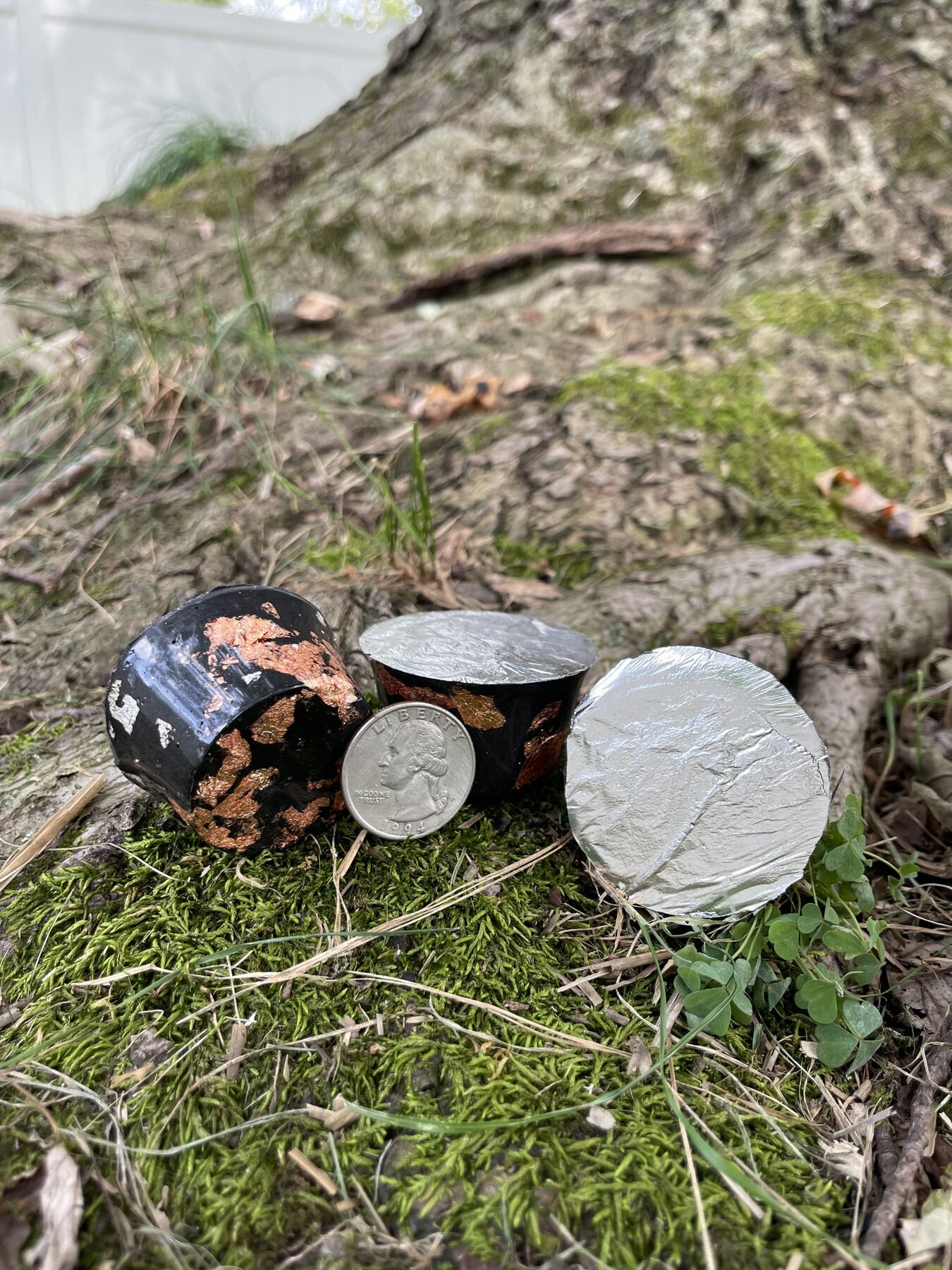 Three hand-cast Peace Pucks with copper inclusions and a quarter outdoors